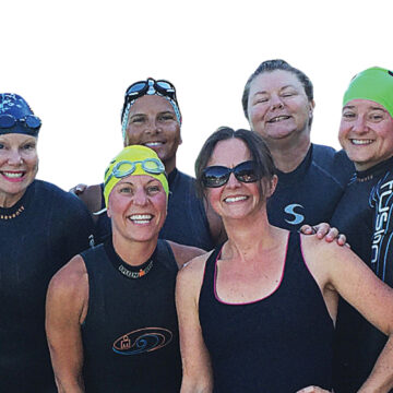 Triathlon coach Christine Schirtzinger poses with women triathletes before a triathlon race.