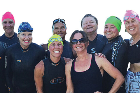 Triathlon coach Christine Schirtzinger poses with women triathletes before a triathlon race.