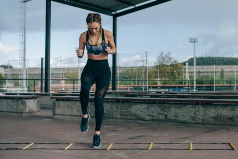 Woman doing single-leg lateral hops over an agility ladder