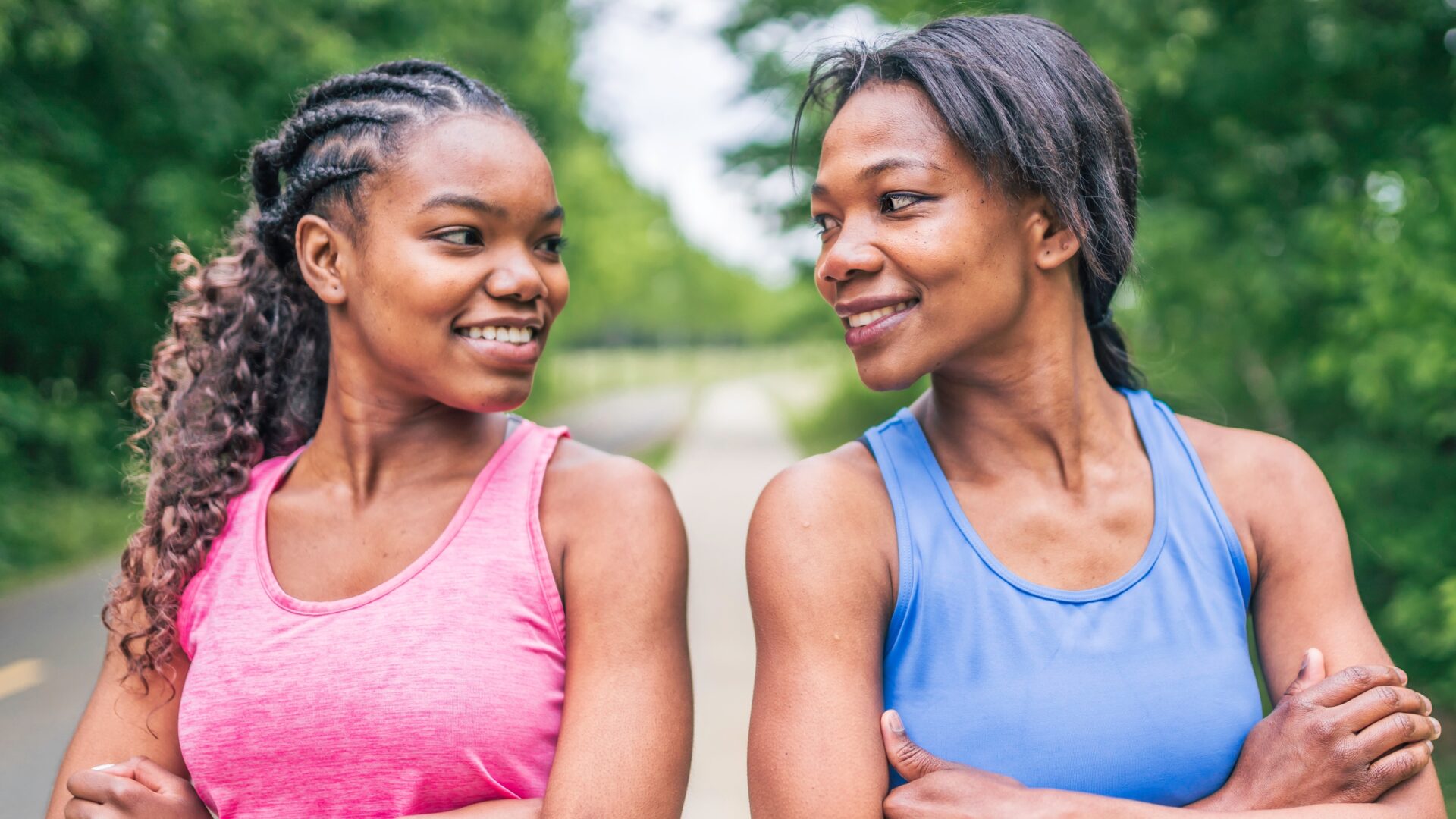 Smiling mother and daughter duo looking at each other after going for a run.