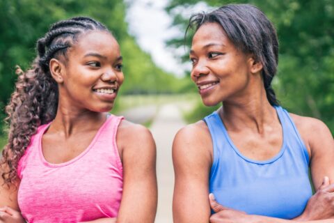 Smiling mother and daughter duo looking at each other after going for a run.