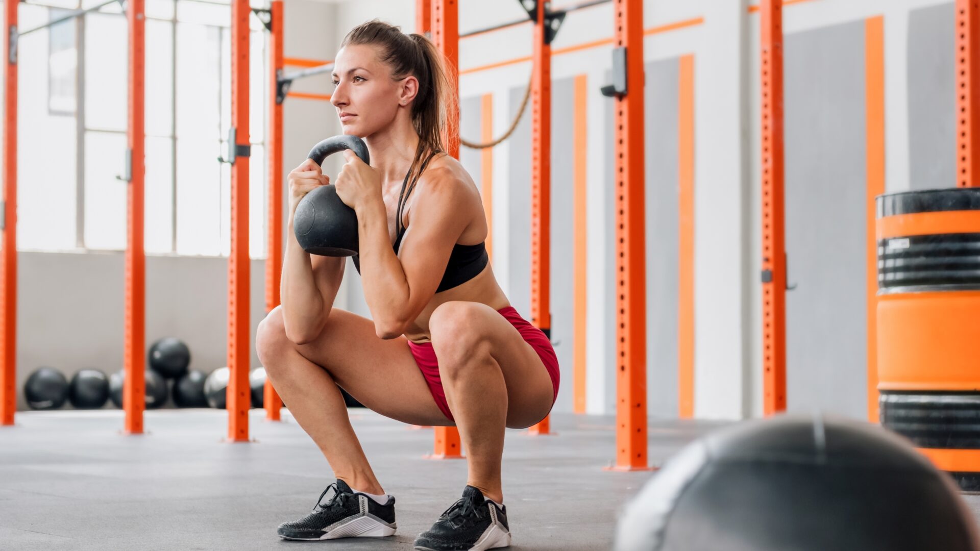 A woman at the gym performing a deep squat with a kettlebell